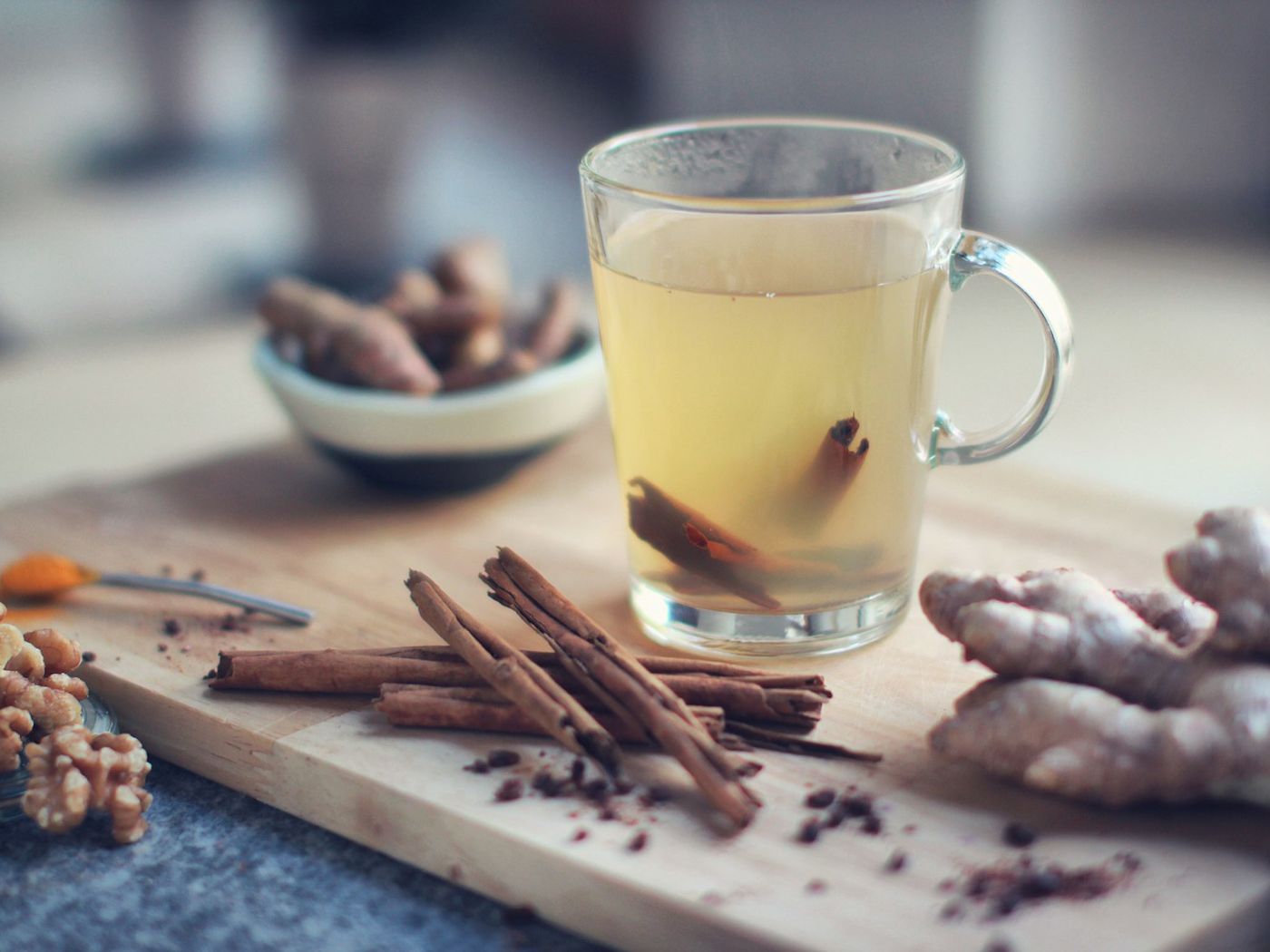 桌上一杯熱飲，旁邊放著老薑與肉桂棒